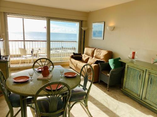 un salon avec une table, des chaises et un canapé dans l'établissement Appartement avec accès direct à la plage, balcon et garage privé - FR-1-92-690, à Les Sables-dʼOlonne