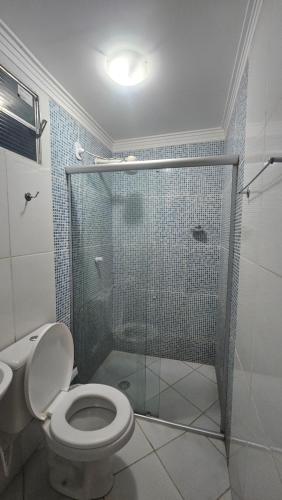 a bathroom with a toilet and a glass shower at Pousada Casa Bella in Itaberaba