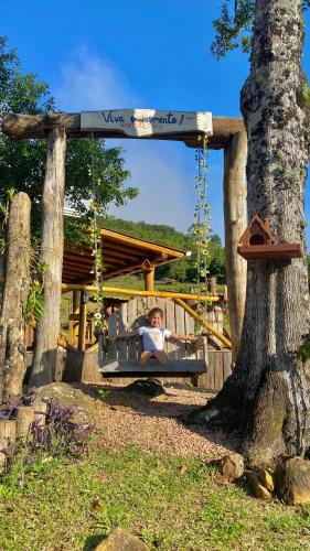 a boy sitting in a swing in a playground at Alto da colina Caraá RS in Caraá