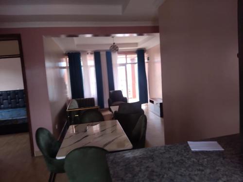 sala de estar con mesa, sillas y ventanas en Kigali Peace Abode, en Kigali