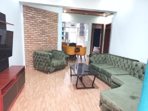 - un salon avec des canapés verts et un mur en briques dans l'établissement Kigali Peace Abode, à Kigali