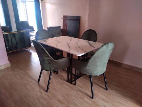 d'une table à manger entourée de 4 chaises vertes. dans l'établissement Kigali Peace Abode, à Kigali