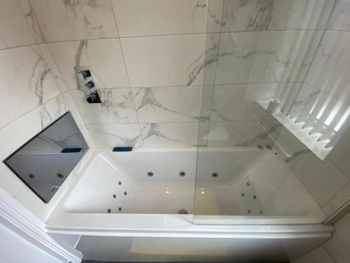 y baño con bañera blanca y paredes de mármol. en Entire Southgate House en Elland
