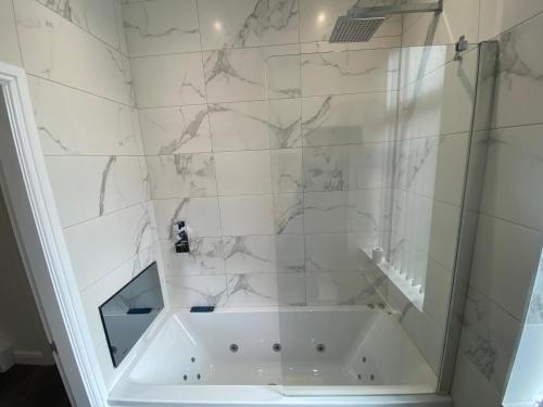 La salle de bains est pourvue d'une baignoire avec des murs en marbre. dans l'établissement Entire Southgate House, à Elland