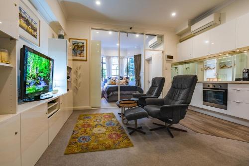 a living room with two chairs and a flat screen tv at Oversized Potts Point Studio in Sydney