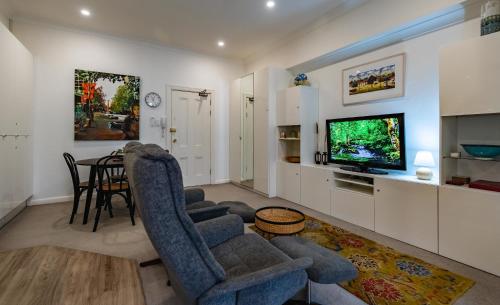 a living room with a couch and chairs and a television at Oversized Potts Point Studio in Sydney