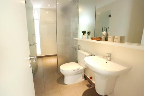 a white bathroom with a toilet and a sink at Villa Biển - Oceanami Resort Long Hải in Long Hai