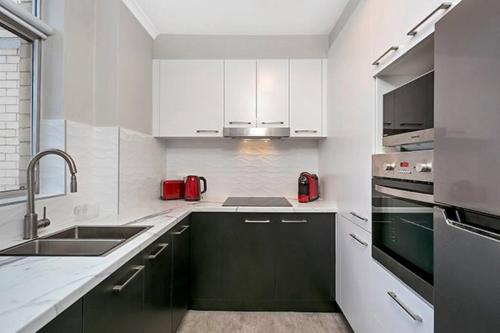 a white kitchen with black cabinets and a sink at RAND3 - Cosy Apartment - Great Location, Easy CBD Access in Sydney