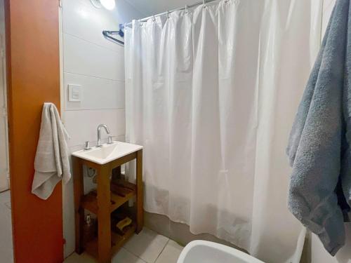 baño con cortina de ducha blanca y lavamanos en Cozy Studio in Caballito Your Gateway to Buenos Aires en Buenos Aires