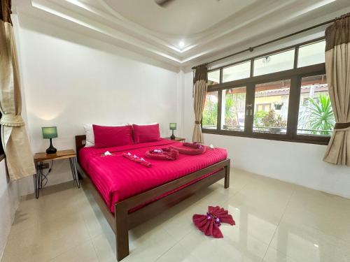 a bedroom with a large pink bed with red sheets at Amara Beach Resort Koh Phangan in Haad Yao