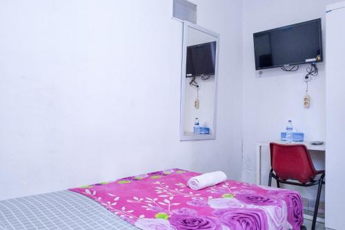 ジャカルタにあるHotel Global Syariahのベッドルーム(ベッド1台、赤い椅子、テレビ付)