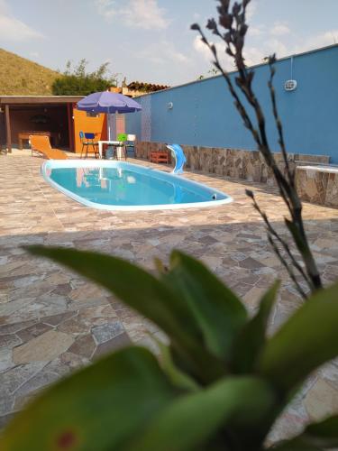 einen Pool mit einem Tisch und einem Sonnenschirm in der Unterkunft Casa de campo Maria&Maria próximo a cidade de Juiz de Fora MG in Juiz de Fora