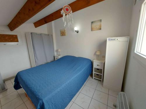 - une chambre avec un lit bleu et un réfrigérateur dans l'établissement Appartement 2 pièces meublé avec mezzanine et terrasse, accès direct à la plage, parking inclus - FR-1-326-798, à Marseillan
