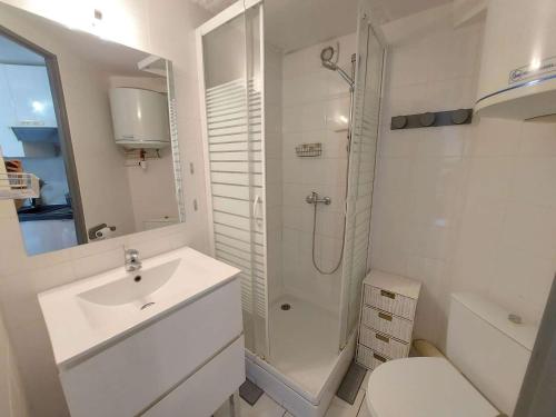 une salle de bain blanche avec un lavabo et une douche dans l'établissement Appartement 2 pièces meublé avec mezzanine et terrasse, accès direct à la plage, parking inclus - FR-1-326-798, à Marseillan