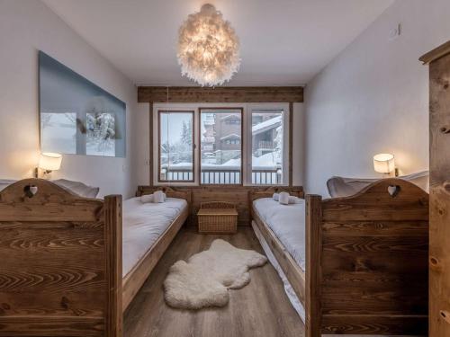 une chambre avec deux lits et un lustre dans l'établissement Courchevel 1850 - 55 m² - 4 pers - skis aux pieds - parking - FR-1-631-184, à Courchevel
