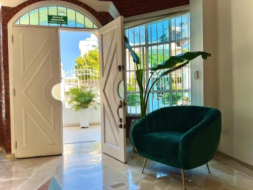 a green chair sitting in front of an open door at Charme 64 Hotel Boutique Aeropuerto in Cartagena de Indias