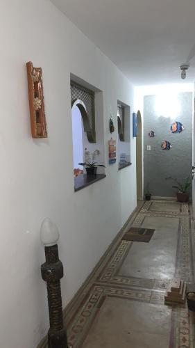 een kamer met een witte muur en een hal met schilderijen bij Pousada Tropical in Marataizes