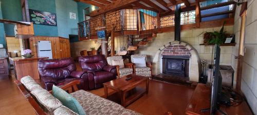 sala de estar con muebles de cuero y chimenea en Eastern Reef Cottages, en Port Campbell