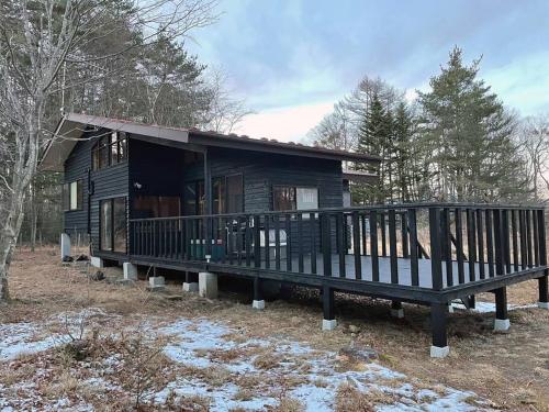 a wooden cabin with a large porch in the woods at ＨARUNA VILLA 浅間山麓、貸切コテージ、アクセス抜群 in Kita-karuizawa