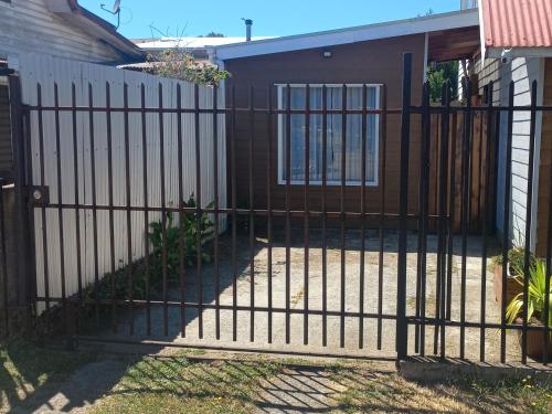 an iron fence with a gate in front of a house at Mini Casa Rocura Valdivia in Valdivia