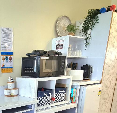 a microwave oven sitting on top of white shelves at Dolphin Heads - Resort Unit - Absolute Beachfront! - Whitsunday Getaway! in Mackay