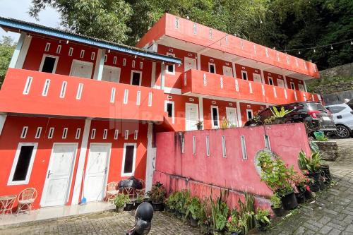 een rood gebouw met auto's ervoor geparkeerd bij Penginapan Gindo Sidebuk Debuk Berastagi RedPartner in Berastagi