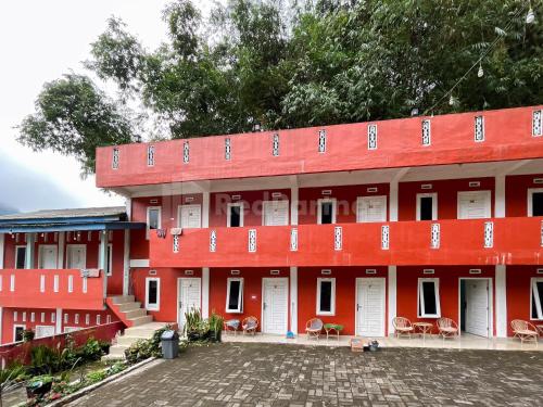 een rood gebouw met witte deuren en stoelen bij Penginapan Gindo Sidebuk Debuk Berastagi RedPartner in Berastagi