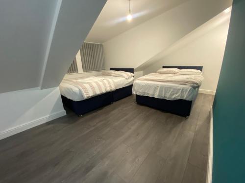 two beds in a small room with wood floors at Entire Southgate apartment in Elland