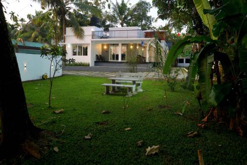 a backyard with a picnic table in front of a house at Serene Retreat in Cochin