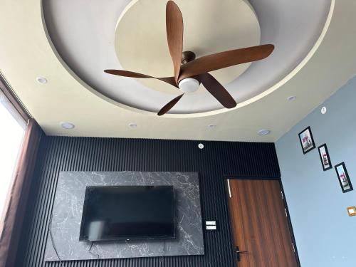 Elle comprend un plafond avec un ventilateur de plafond et une télévision. dans l'établissement Yash Guest house, à Pīrthala