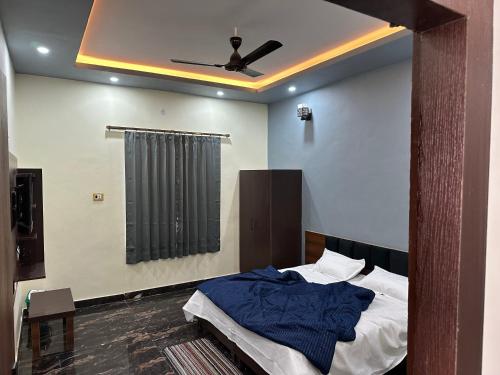 - une chambre avec un lit et un ventilateur de plafond dans l'établissement Yash Guest house, à Pīrthala