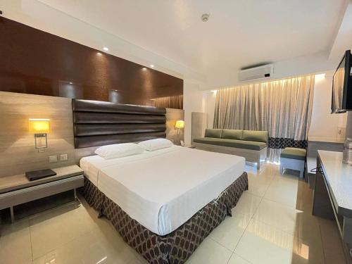 a hotel room with a large bed and a couch at Prime Asia Hotel in Angeles