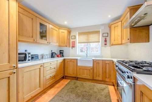 a kitchen with wooden cabinets and a stove top oven at Tarporley Holiday Cottage in Tarporley