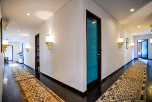 a hallway with white walls and a door and a rug at Melo Suites Hotel in Seminyak