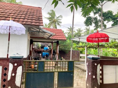 a building with a gate and two umbrellas at Aryana Guest House in Midang