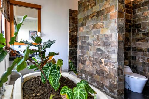 a bathroom with a brick wall and plants at Melo Suites Hotel in Seminyak