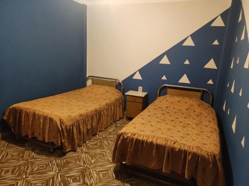 - une chambre avec 2 lits et un mur bleu dans l'établissement HOTEL AMERICA, à Tarija