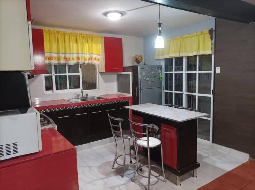 a kitchen with red cabinets and a island with bar stools at casa de mamá in Santa María Azompa