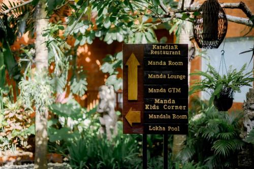 a sign in a garden with plants at Fourteen Roses Boutique Hotel, Kuta in Legian