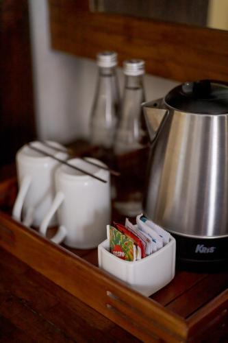 a counter with a coffee pot and packets of sugar at Fourteen Roses Boutique Hotel, Kuta in Legian