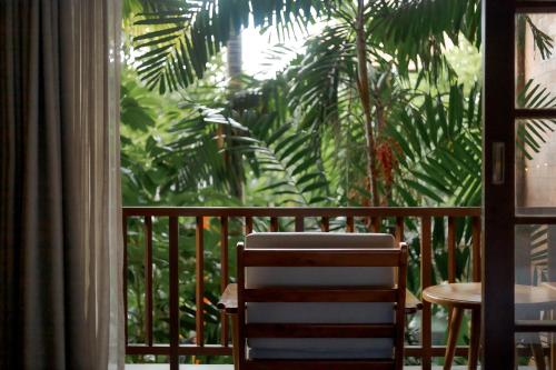 a balcony with a table and chairs and palm trees at Fourteen Roses Boutique Hotel, Kuta in Legian