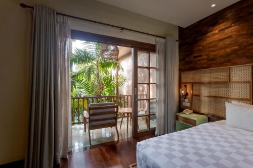 a bedroom with a bed and a view of a balcony at Fourteen Roses Boutique Hotel, Kuta in Legian