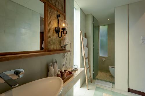 a bathroom with a sink and a mirror and a tub at Fourteen Roses Boutique Hotel, Kuta in Legian