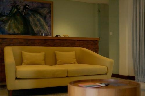 a yellow couch in a living room with a table at Fourteen Roses Boutique Hotel, Kuta in Legian