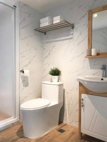 a white bathroom with a toilet and a sink at 所在行旅2館-渡咕所在 UrbanAbode2-DUGU in Taipei