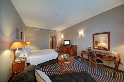 a hotel room with a bed and a desk at Royal Ascot Hotel in Dubai
