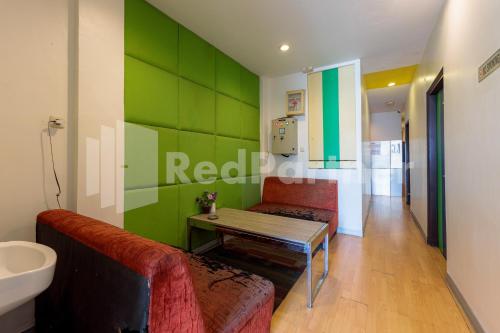 uma sala de estar com uma mesa e uma parede verde em Ichiza Room RedPartner em Jakarta