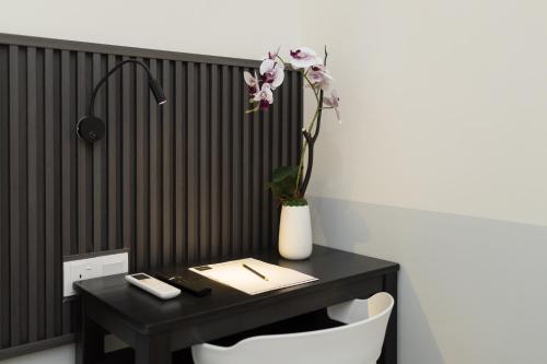 a black desk with a vase with a flower on it at Hotel Luma Senawang in Seremban