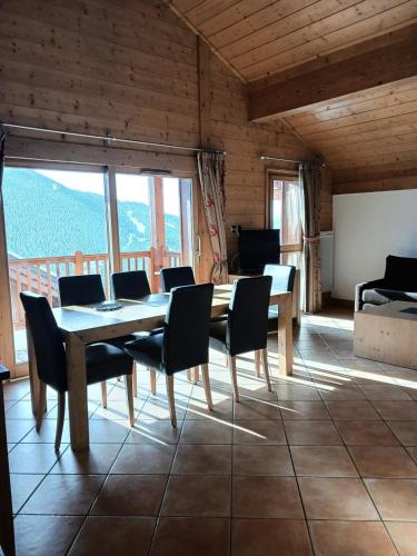 ein Esszimmer mit einem Tisch, Stühlen und Fenstern in der Unterkunft Résidence L'oree Des Neiges - 4 Pièces pour 6 Personnes 711 in Peisey-Nancroix