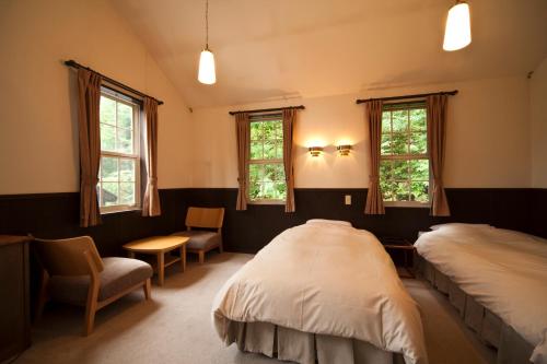 sypialnia z 2 łóżkami, krzesłem i oknami w obiekcie Poetical w mieście Matsumoto